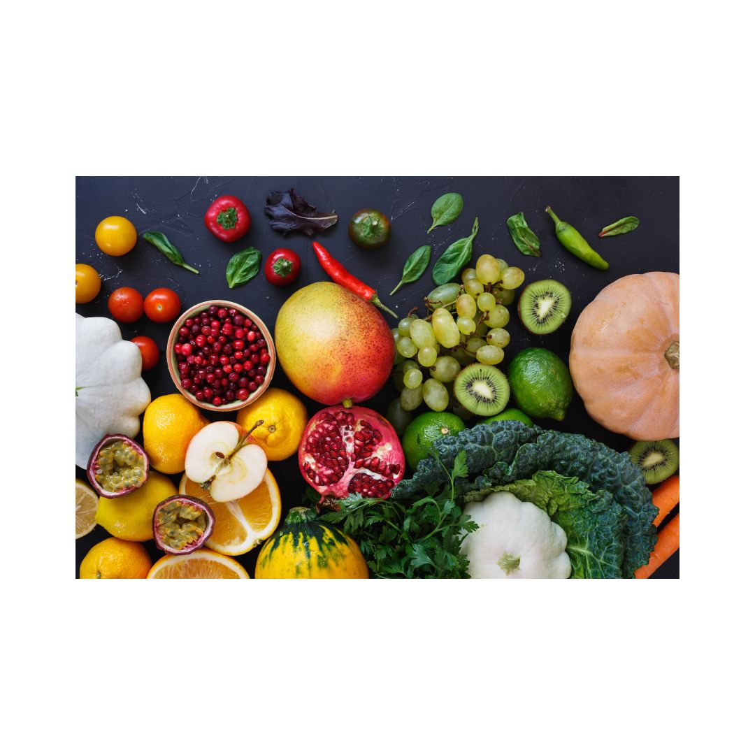 An assortment of fresh fruits and vegetables, including apples, oranges, pumpkins, squash, grapes, and broccoli, arranged on a dark background.