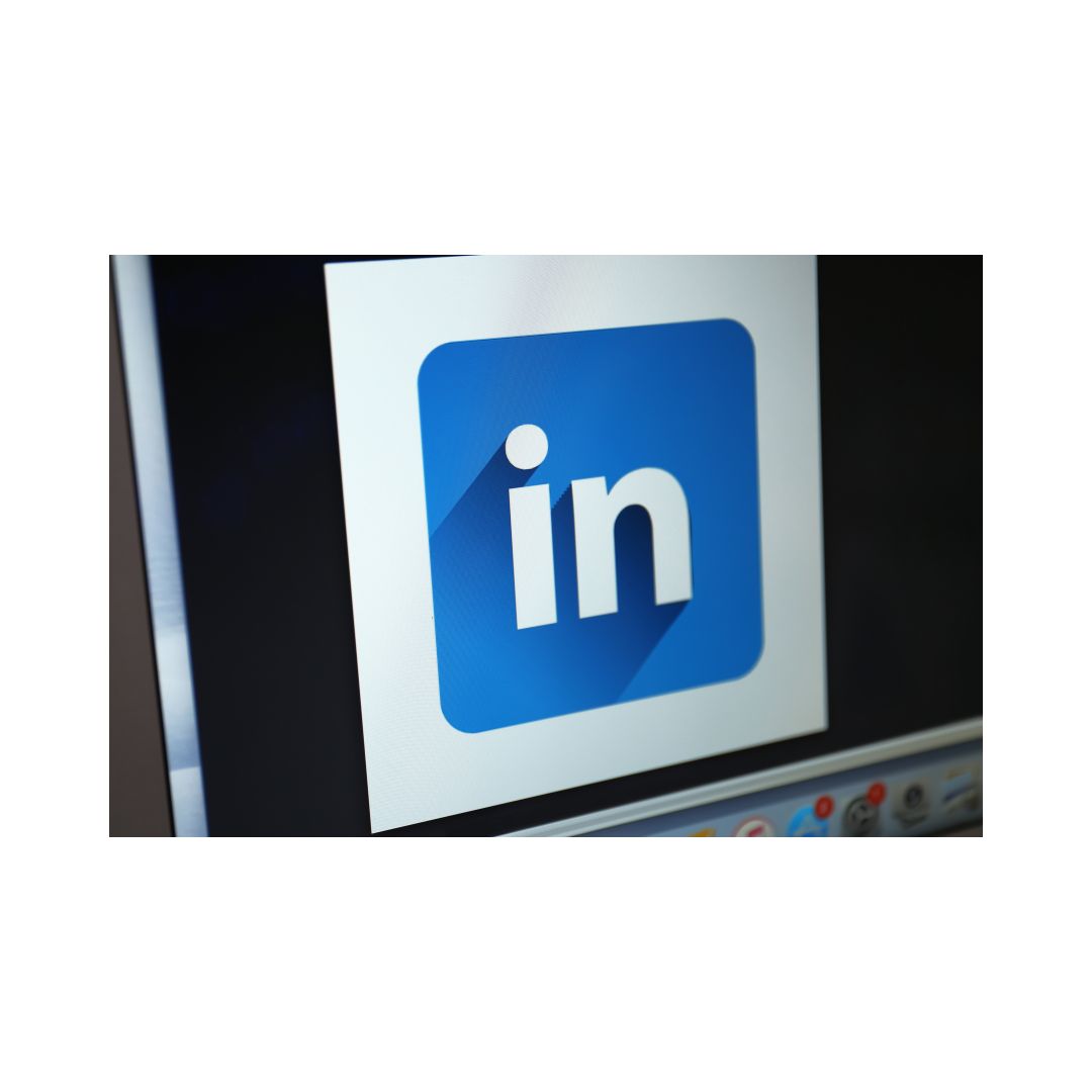 The image shows the LinkedIn logo, which is a blue square with a white arrow and the letter 'L' inside it, on a monitor or screen.