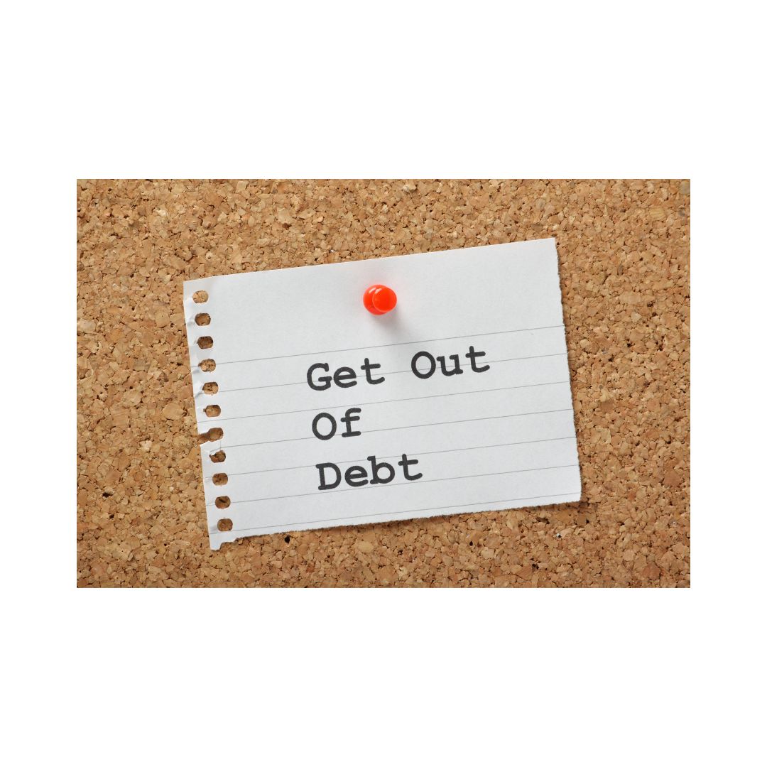 A piece of paper with the text 'GET OUT OF DEBT' written in capital letters, attached to a corkboard with a red dot on the left side.