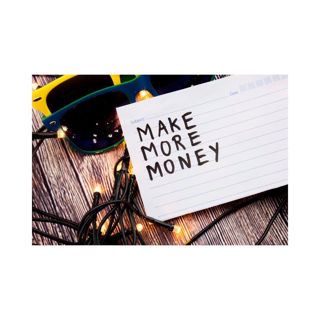 A worksheet with the title 'Make More Money' written in bold black script, placed on a wooden surface with glasses and Christmas lights in the background.