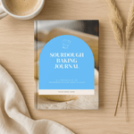 Sourdough Baking Journal on a wooden surface with a cup of coffee and dried plants.