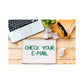 A worksheet with the title 'Check Your Email' written on the first page, placed on a desk alongside a laptop, a notebook, and a pair of glasses.