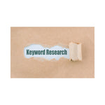 A worksheet titled 'Keyword Research' partially covered by a simulated crumpled paper graphic, indicating a title or section header.